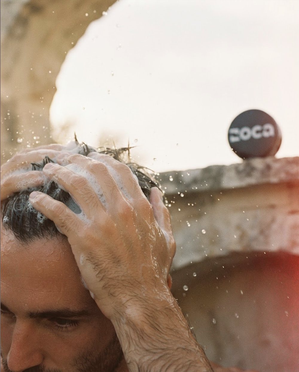 Homem lavando o cabelo ao ar livre, lata Zoca ao fundo
